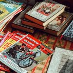 motorcycle magazines and books stacked on top of a table