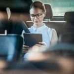 woman sitting in the back seat reading a book