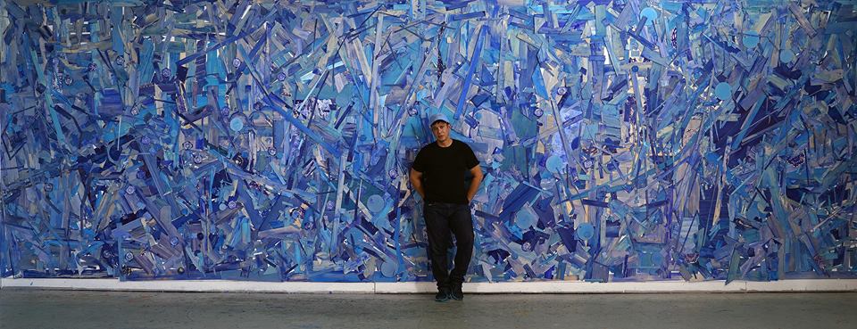 Man standing in front of an abstractly painted blue wall