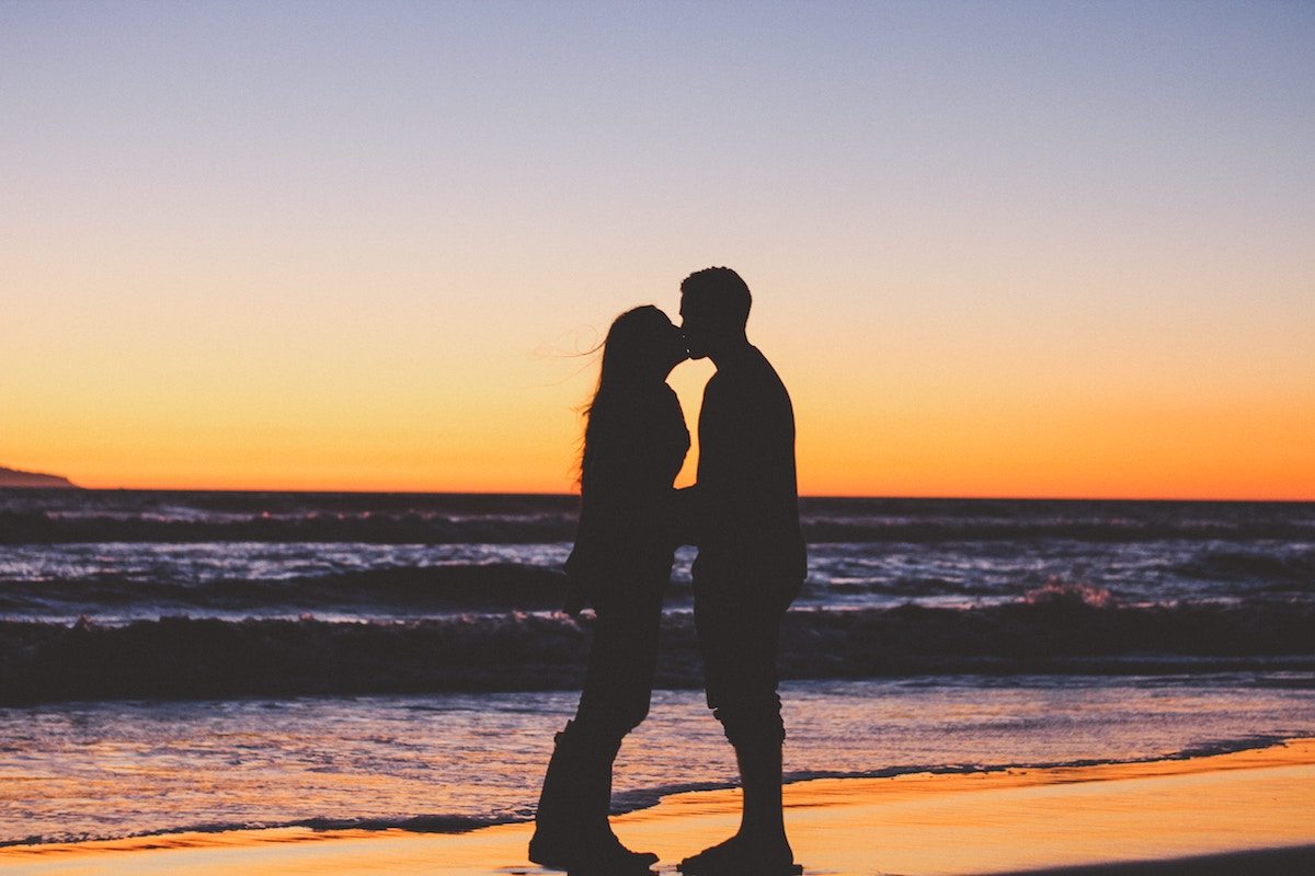 silhouette of couple kissing on the beach at sunset