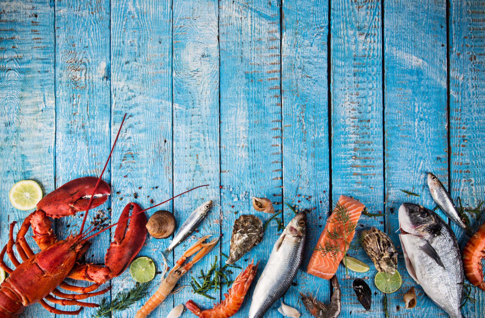 fish and lobster lying on wooden blue table